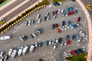 Paved outdoor parking with white road markings, infrastructure filled with cars, view from copter.