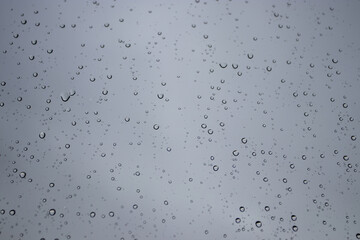 Rain drops on the window glass on the autumn gray sky background