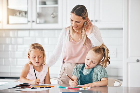 Homework, education and learning during homeschool lesson with their mother on the kitchen counter. Cute little girls doing educational drawing with color pencils assistant or help from their mom