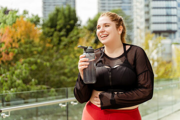 Smiling young woman taking a break after running workout. Plus size model, motivation, training