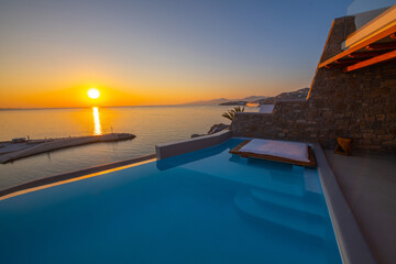 Fototapeta na wymiar Infinity swimming pool in the villa at sunset time, Mykonos, Greece