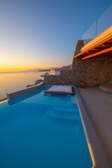 Infinity swimming pool in the villa at sunset time, Mykonos, Greece