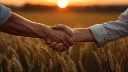 Rolgordijnen Two farmers shake hands in front of a wheat field. © JKLoma