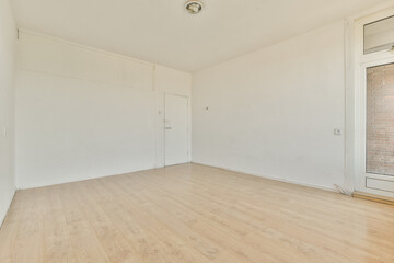 an empty room with white walls and wood flooring on the right, there is a brick wall in the background