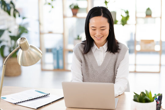 Asian woman, typing and laptop at startup with smile, planning and focus seo management. Young executive, social media content manager and computer in office for schedule, analysis and networking