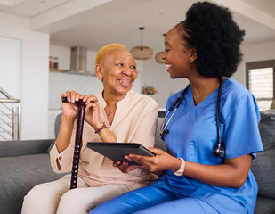Health consultation, nurse and black woman with tablet for medical information or advice online. Smile, conversation and an African nurse helping a senior patient with healthcare on an app in a house - obrazy, fototapety, plakaty