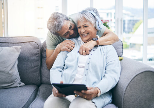 Laughing, hug and couple with a tablet for a website, streaming music or a podcast together. Love, embrace and a senior man and woman with a movie or funny video on technology or listening to audio