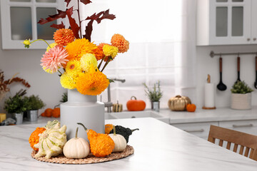 Beautiful autumn bouquet and pumpkins on marble table in kitchen