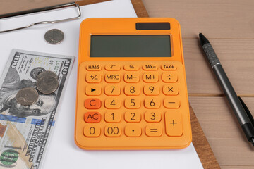 Orange calculator, money, clipboard with paper sheet and pen on table. Retirement concept