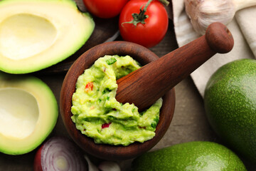 Mortar with delicious guacamole and ingredients on table, flat lay