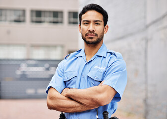 Portrait, man and security guard with arms crossed for police service, protection and safety in city. Law enforcement, bodyguard and serious asian male officer in blue uniform outdoor for town patrol - obrazy, fototapety, plakaty