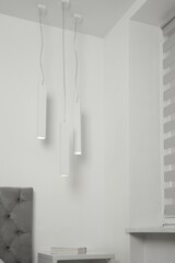 Stylish pendant lamps hanging over nightstand in light room