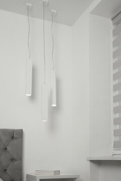 Stylish pendant lamps hanging over nightstand in light room