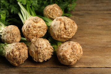 Fresh raw celery roots on wooden table. Space for text