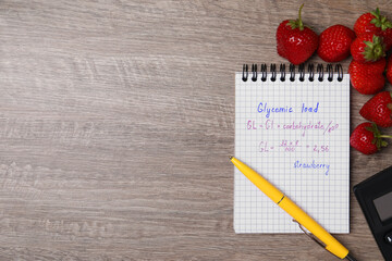 Notebook with calculated glycemic load for strawberry and fresh berries on wooden table, flat lay....
