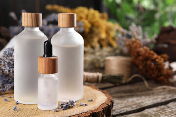 Fototapeta na wymiar Bottles of essential oils and dry lavender flowers on wooden table, space for text. Medicinal herbs