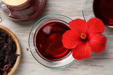 Obraz na płótnie Canvas Delicious hibiscus tea and beautiful flower on light wooden table, flat lay