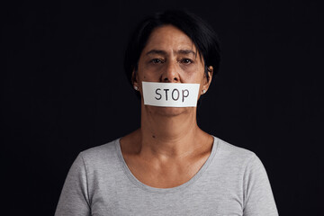 Portrait, stop and censorship with a woman in studio on a black background for gender equality or domestic violence. Face, silence or abuse and a scared female victim with her mouth covered in fear