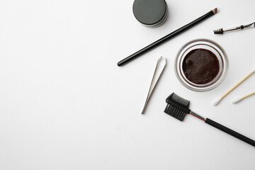 Flat lay composition with eyebrow henna and professional tools on white background, space for text