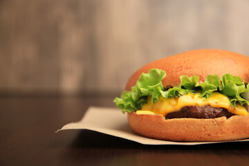 One tasty cheeseburger on wooden table, closeup. Space for text