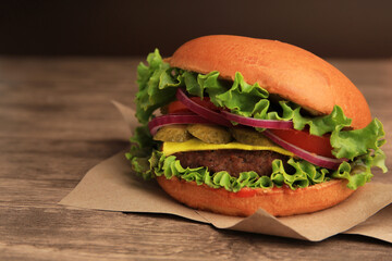One tasty burger on wooden table, closeup. Space for text