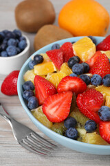 Delicious fresh fruit salad in bowl served on wooden table, closeup