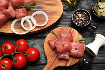 Raw beef meat and different ingredients for cooking delicious goulash on black wooden table, flat lay