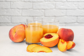 Glasses of delicious peach juice and fresh fruits on white wooden table