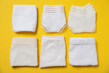 Stylish folded women's underwear on yellow background, flat lay