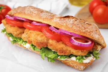 Delicious sandwich with schnitzel on white tiled table, closeup