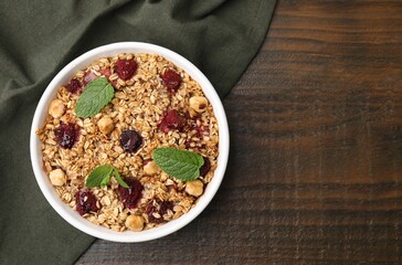 Tasty baked oatmeal with berries and nuts in bowl on wooden table, top view. Space for text