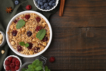 Tasty baked oatmeal with berries and nuts on wooden table, flat lay. Space for text