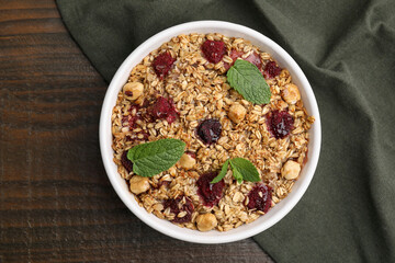 Tasty baked oatmeal with berries and nuts in bowl on wooden table, top view