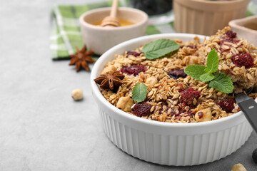 Tasty baked oatmeal with berries, nuts and anise star on light table, closeup. Space for text