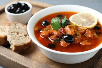 Meat solyanka soup with sausages, olives and vegetables in bowl served on table, closeup