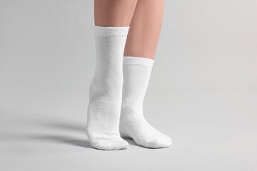 Woman in stylish white socks on light grey background, closeup