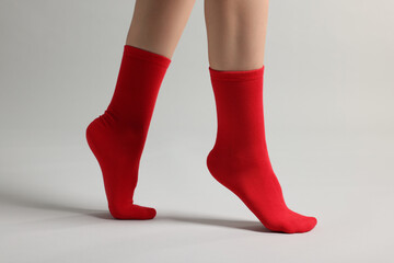 Woman in stylish red socks on light grey background, closeup