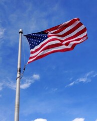 Flag of USA blowing on a pole against blue sky