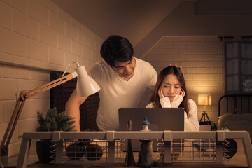 Concerned couple looking at a laptop screen in a softly lit room, both man and woman appears...