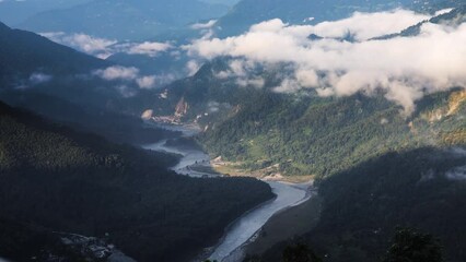 Timelapse video during sunrise with winding river teesta and Himalayan hills and mountains. White clouds drifting. Daylight covering the area in the morning.