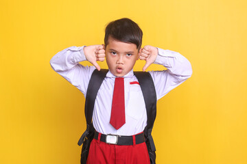 Adorable elementary school student wear uniform showing thumbs down with disappointed expression