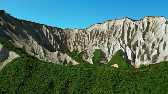 Beautiful aerial of the white cliffs on the south coast of England. Clip. Green summer forested hills and blue sky.