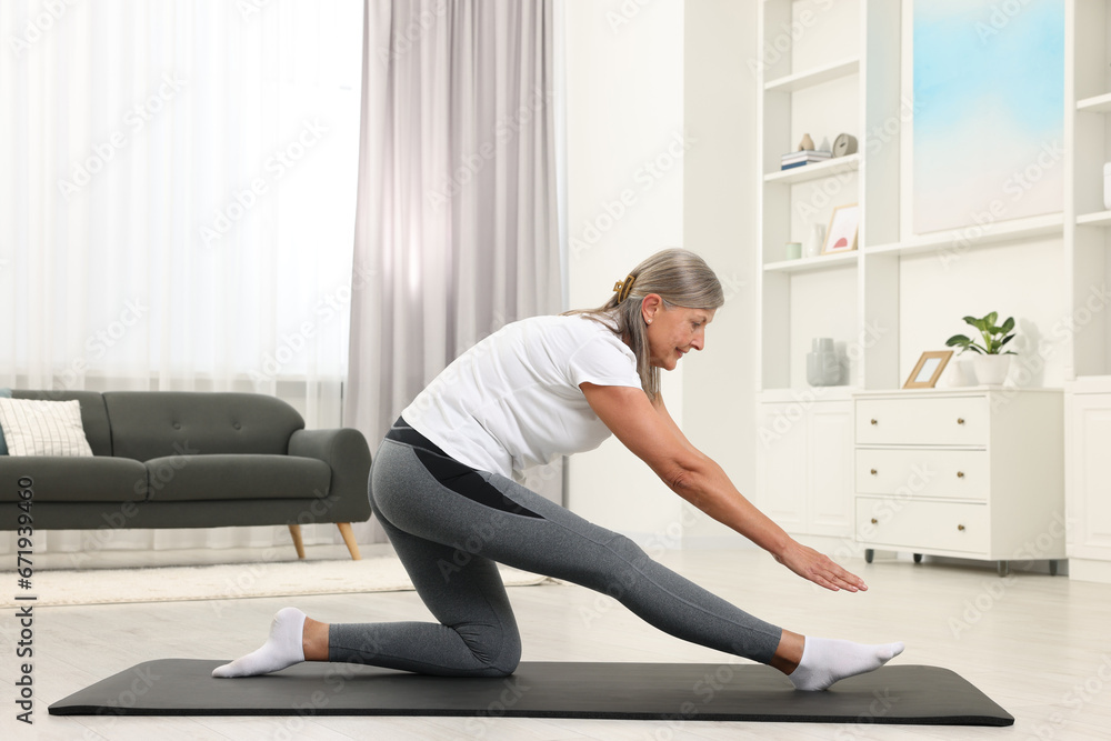 Sticker Happy senior woman practicing yoga on mat at home