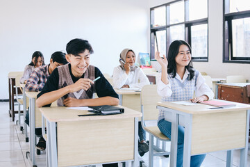 Group of college students sitting and laughing in classroom 