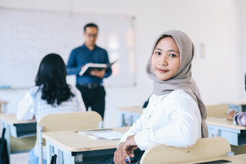 Portrait of smiling asian female student sitting at desk in classroom at university