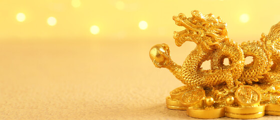 Golden figurine of Chinese dragon on yellow background with space for text