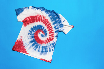Red blue and white tie dye T-shirt on a blue background. The concept of self-dyeing clothes.