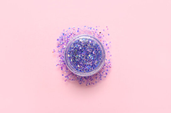 Jar of purple glitter on pink background