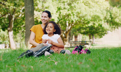Fototapeta premium Family, mother and kid in park with rollerblading outdoor, relax on grass and fun in nature with happy people. Woman, girl and taking a break, sports and quality time together with love and care