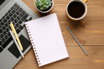 Notebook with laptop and cup of tasty coffee on wooden background